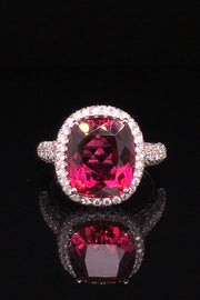 Platinum ring with a cushion rubellite and  diamond pave on a black background.