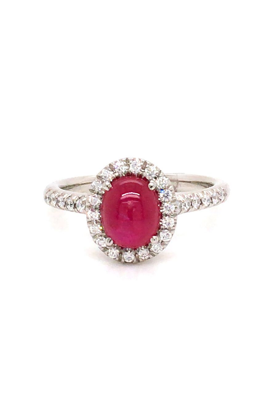 Platinum ring with a ruby cabochon and diamond halo on a white background.