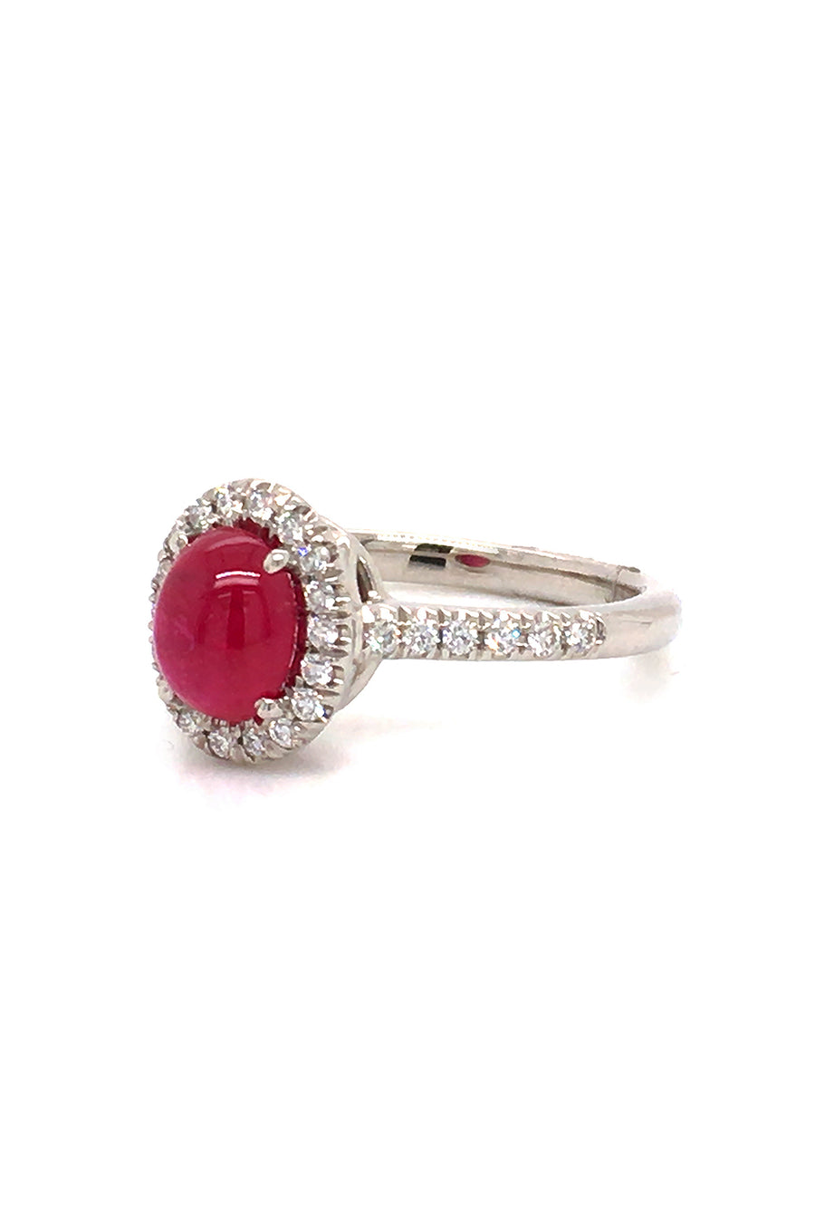 Angle view of platinum ring with a ruby cabochon and diamond halo on a white background.