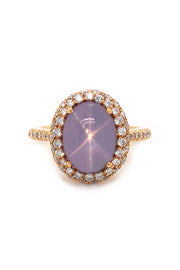 Lavender star sapphire ring with a diamond halo in 20K pink gold on a white background.