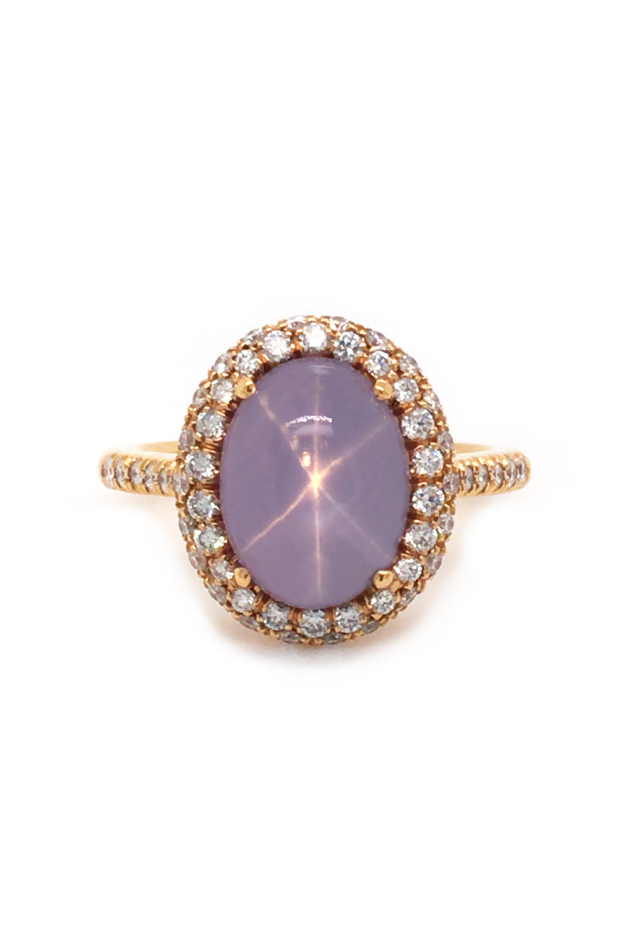 Lavender star sapphire ring with a diamond halo in 20K pink gold on a white background.