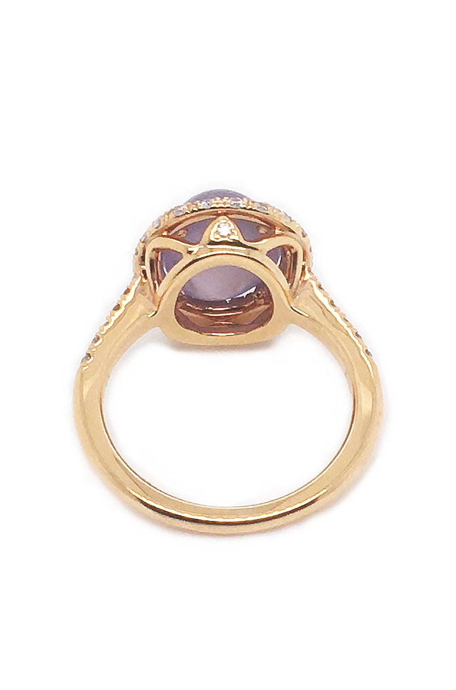 Back view of lavender star sapphire ring with a diamond halo in 20K pink gold on a white background.
