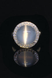 18K white gold ring with cat's eye moonstone gemstone and diamonds on black background