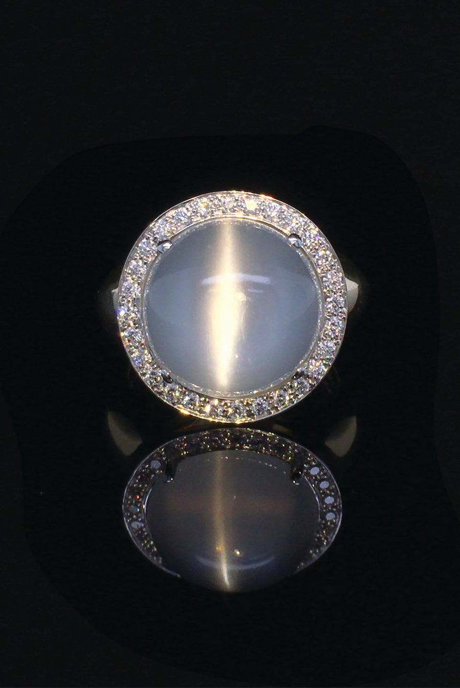 18K white gold ring with cat's eye moonstone gemstone and diamonds on black background