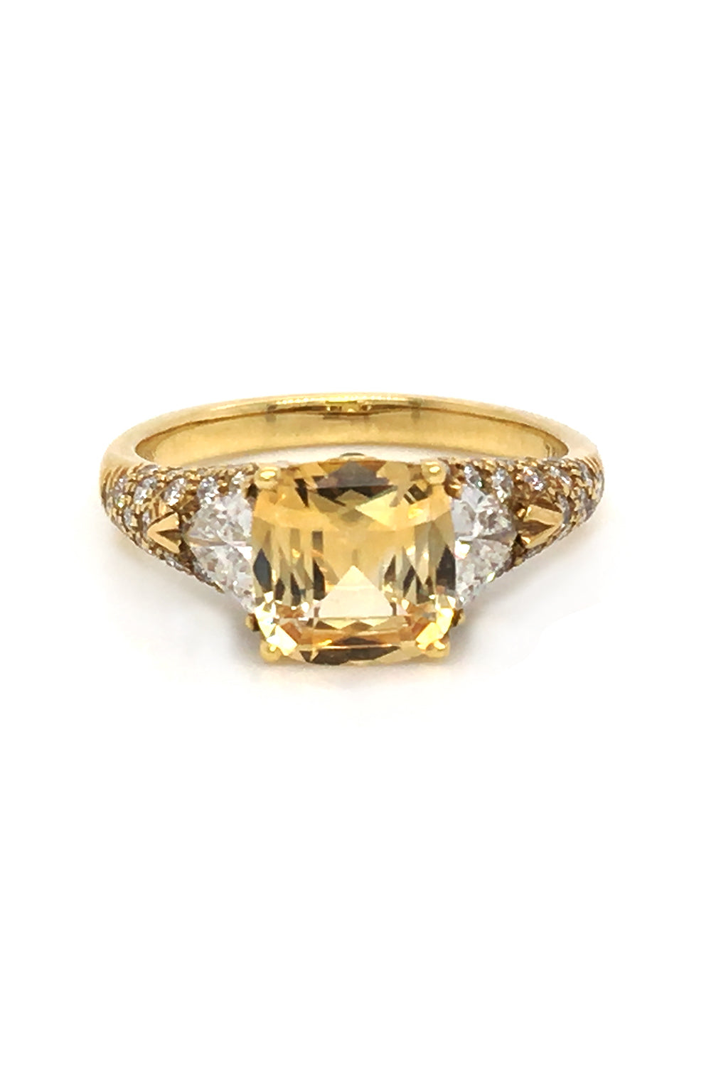 18K yellow gold ring with a yellow sapphire, trilliant diamonds, and pavé diamonds on white background.