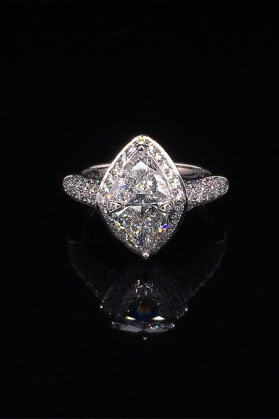 Platinum ring with two trilliants surrounded by pavé diamonds on a black background.