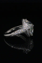 Side view of platinum ring with two trilliants surrounded by pavé diamonds on a black background.