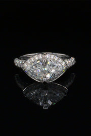 A platinum ring with two trilliant diamonds and brilliant diamonds with  two pink sapphires beneath on a black background.