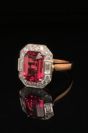 Angle view of rubellite set in platinum with diamonds on 20K pink gold ring on black background.