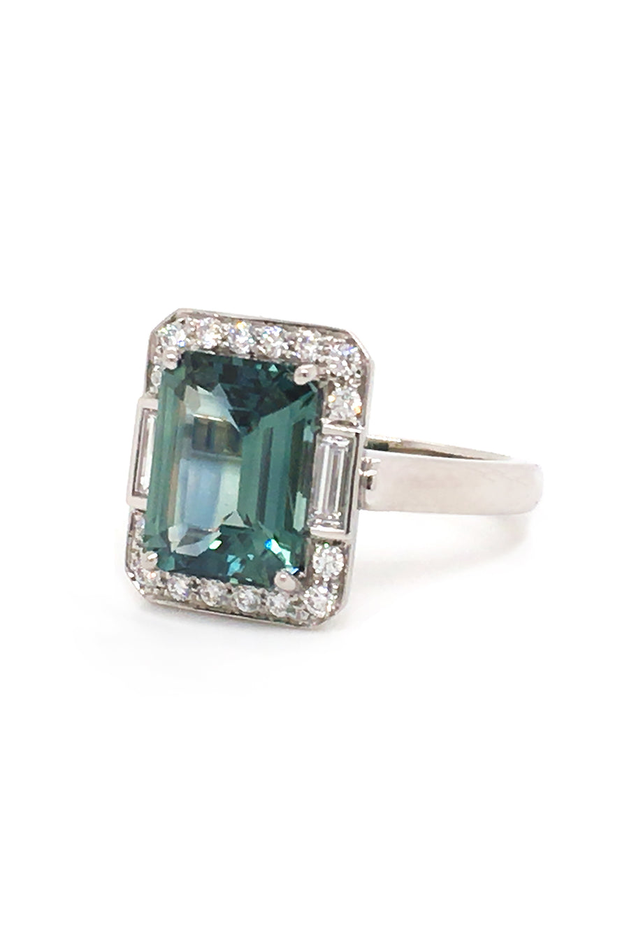 Side view of emerald-cut green sapphire with baguettes and brilliant diamonds in platinum on a white background