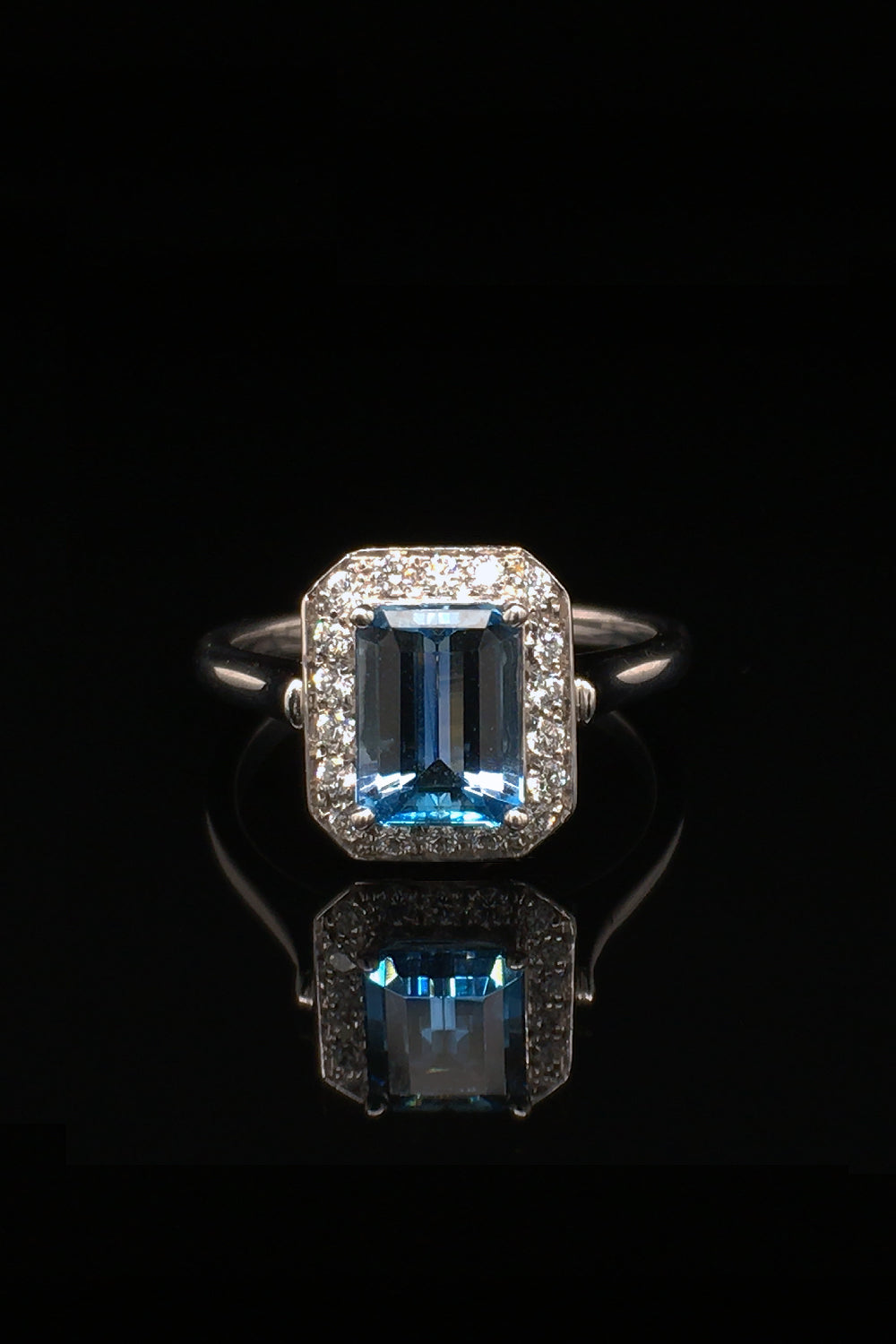 18K white gold ring with an aquamarine and diamonds on black background.