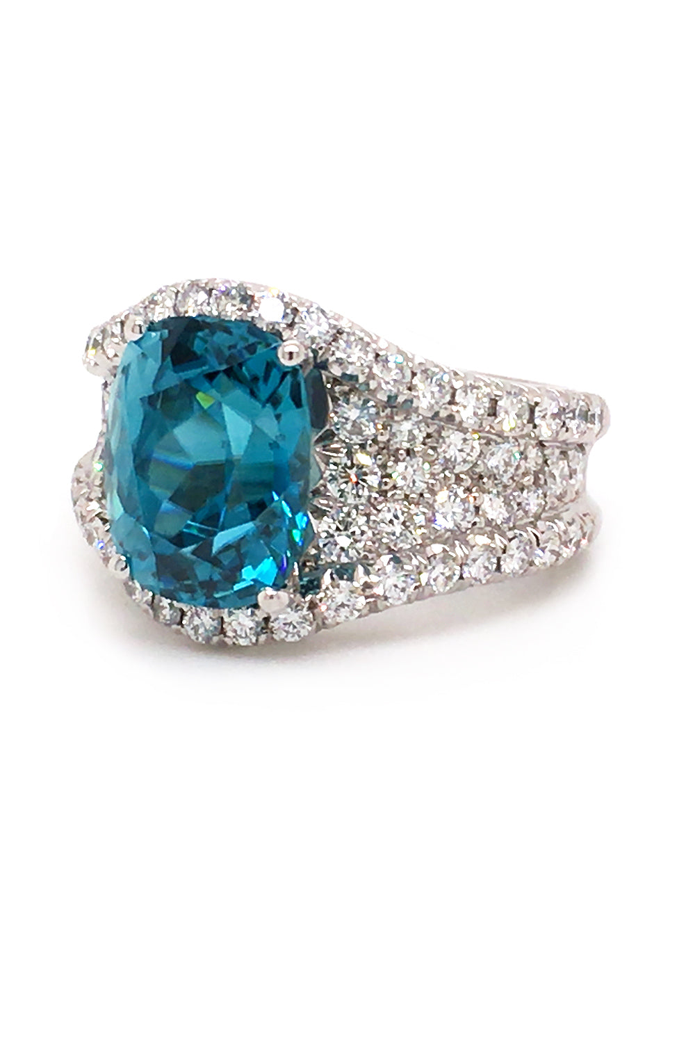 Angle view of  platinum ring with a blue zircon, sapphire accents, and diamonds on a white background