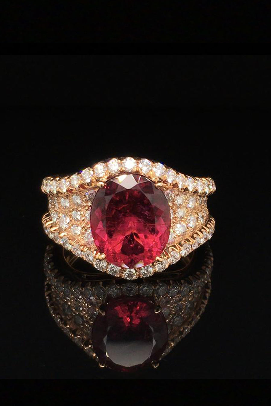 20K pink gold ring with a rubellite and diamond pave on a black background