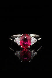 Platinum ring with oval ruby and two half-moon diamonds on a black background