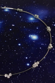 Closeup of platinum wire necklace with diamond clusters on a starry background