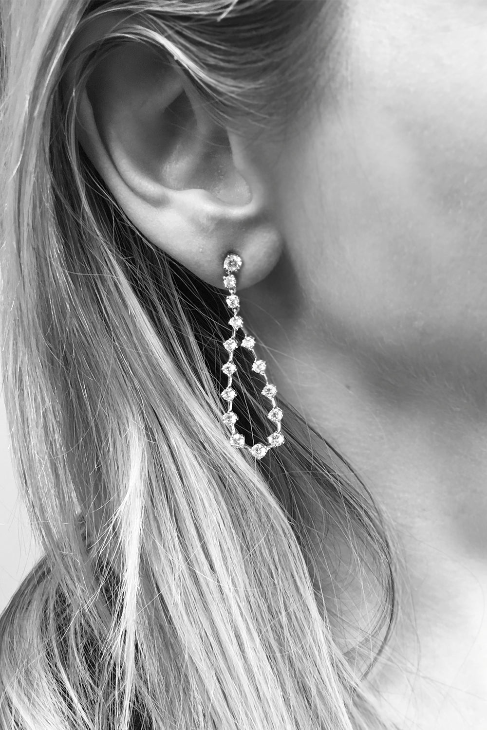 Closeup of woman's ear wearing diamond pear shape earrings