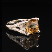 Angle view of 18K white gold ring with a golden zircon and diamonds on a black background.