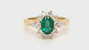 Video of rotating ring with 18K gold ring featuring an oval emerald with diamonds on a white background