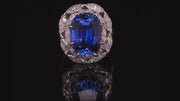 Video of rotating ring with blue gemstone and diamonds on black background