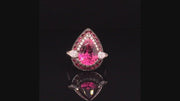 Video of rotating ring with pink and red gemstones and diamonds on black background