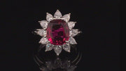 Video of rotating platinum ring featuring a ruby surrounded by pear shape diamonds black background.