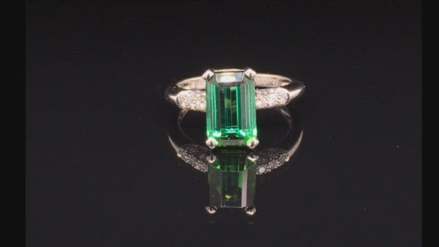 Video of rotating ring with green gemstone and diamonds on black background
