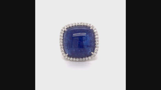 Video of rotating 18K white gold ring with a cushion cabochon tanzanite with a diamond halo on a white background