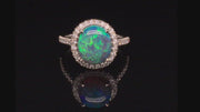 Video of rotating platinum ring with a black opal and diamond halo on a black background.