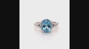 Video of rotating ring with blue gemstone and diamonds on white background