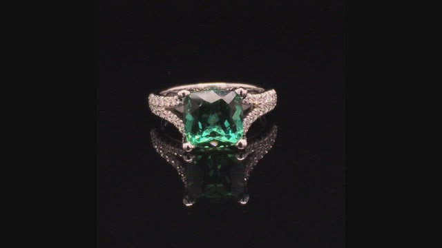 Video of rotating ring with green gemstone and diamonds on black background