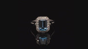 Video of rotating ring with blue gemstone and diamonds on black background