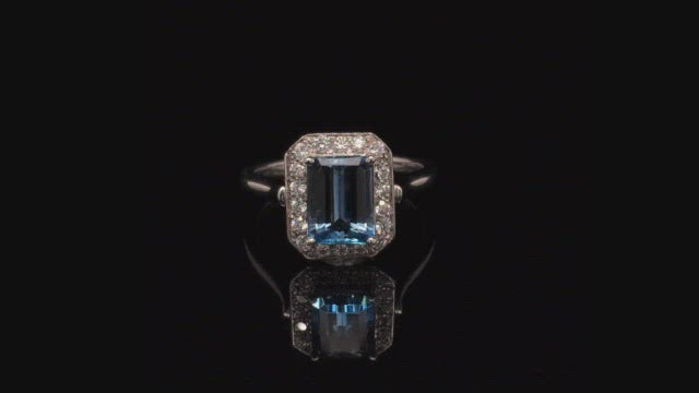 Video of rotating ring with blue gemstone and diamonds on black background