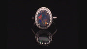 Video of rotating 18K white gold ring with a black opal surrounded with brilliant diamonds on a black background.