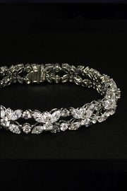 Closeup of platinum bracelet with marquise and brilliant diamonds on a black background.