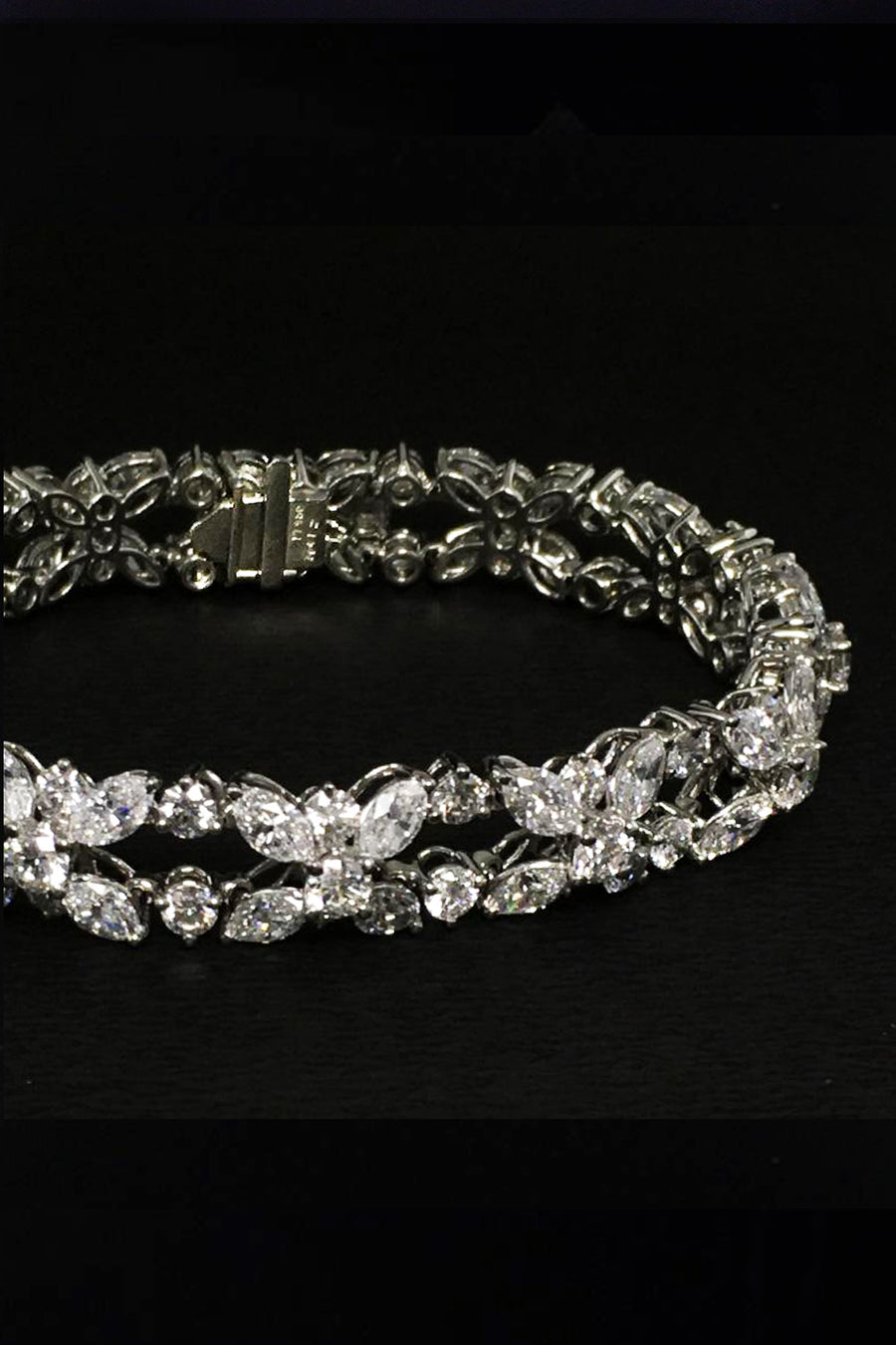 Closeup of platinum bracelet with marquise and brilliant diamonds on a black background.