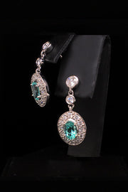 Angle view of platinum earrings with African paraibas and diamonds diamonds on a black background