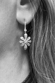 Closeup of woman with flower earring with diamonds and lever-back closure.