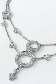 Close-up of a platinum necklace with lace-inspired motif with diamonds on a white background.