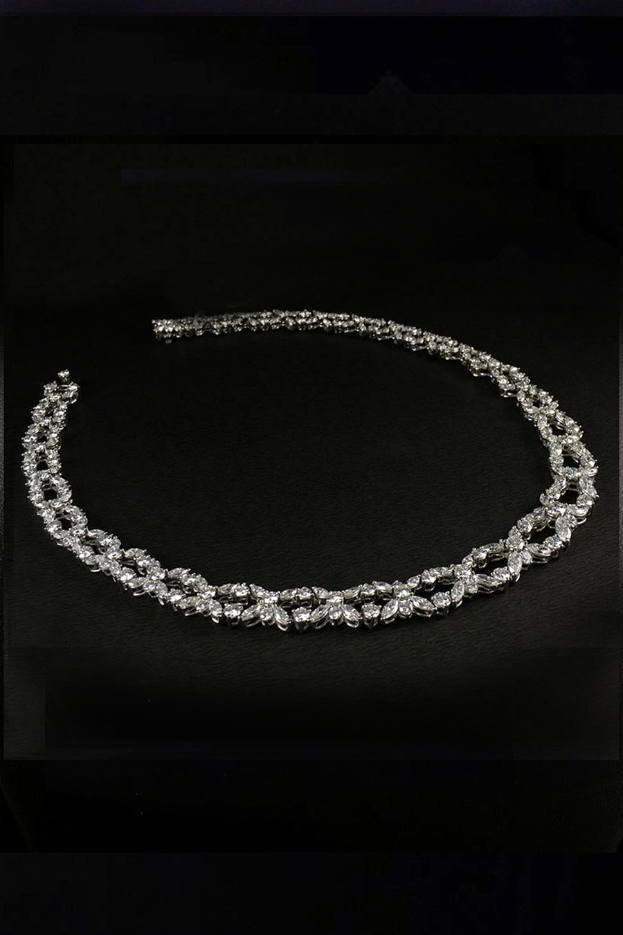 Platinum necklace with marquise and brilliant diamonds laying down on a black background