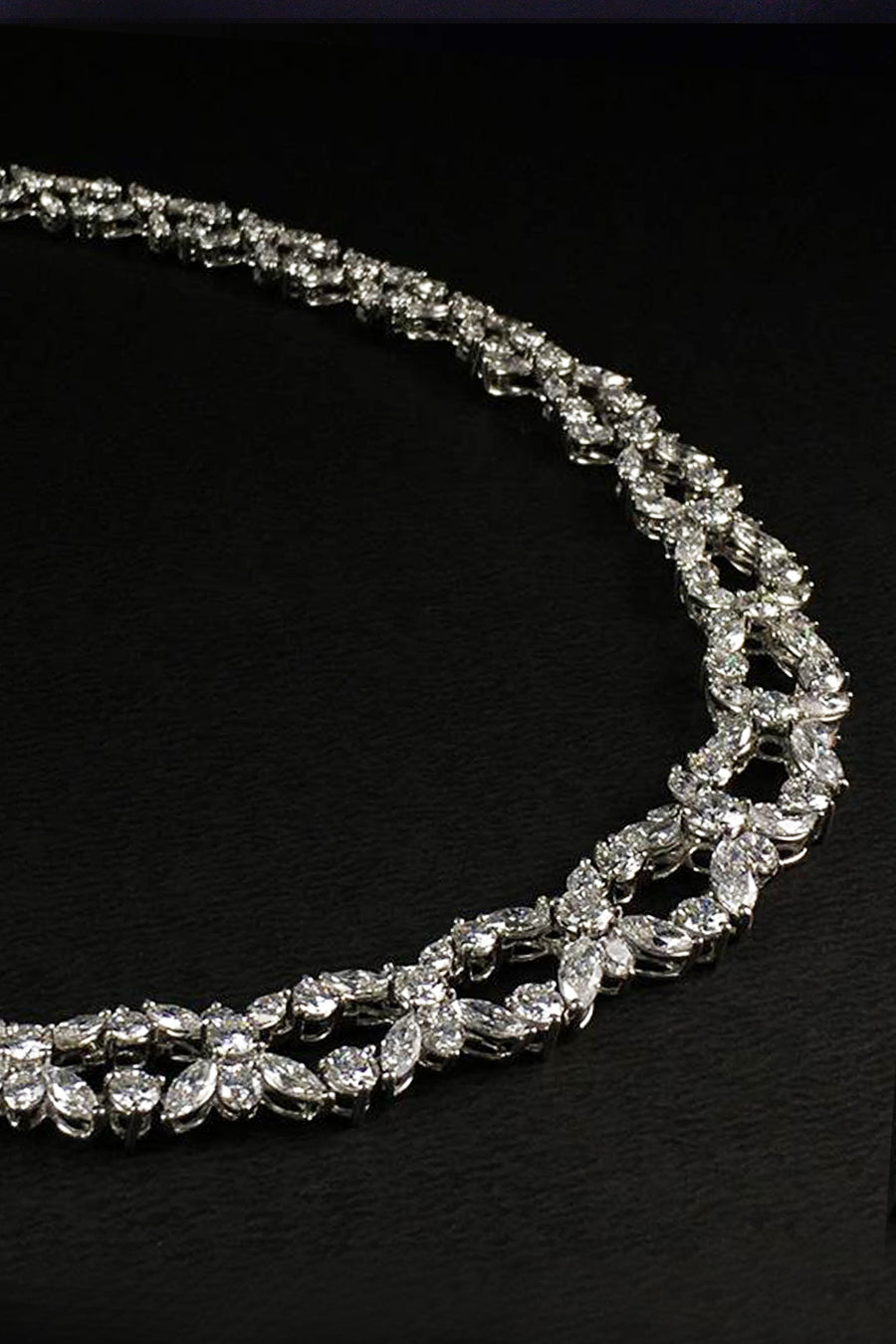 Closeup of platinum necklace with marquise and brilliant diamonds on a black background