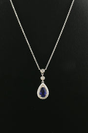 Pear-shaped blue sapphire and diamond necklace in platinum on black background.