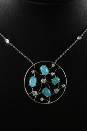 Circular platinum pendant with mosaic motif and Brazilian paraiba cabochons and on a black neck display