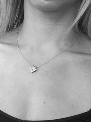 Closeup of woman's neck wearing flower pendant