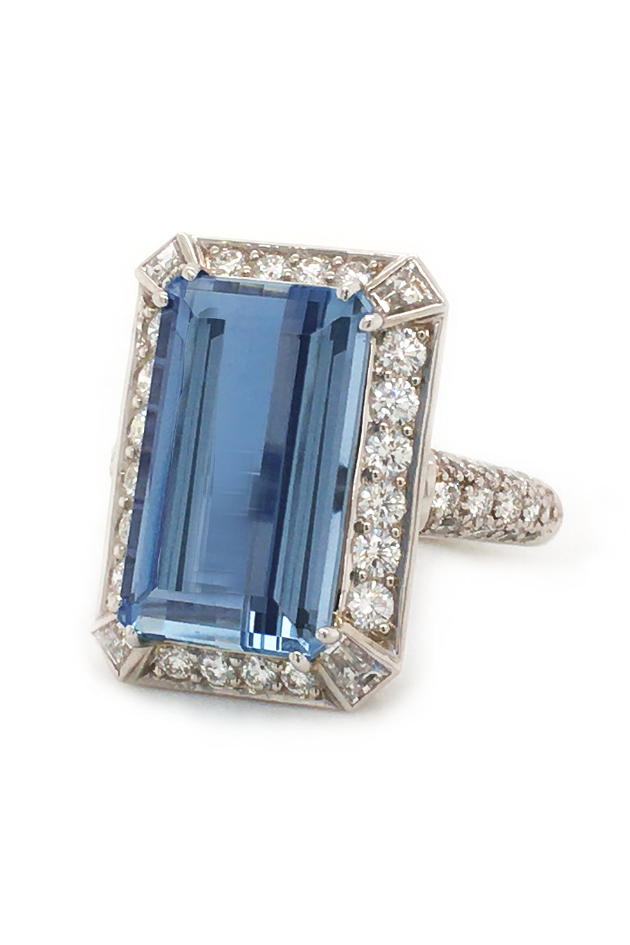 An emerald-cut aquamarine with round diamonds set in a platinum  on a white background