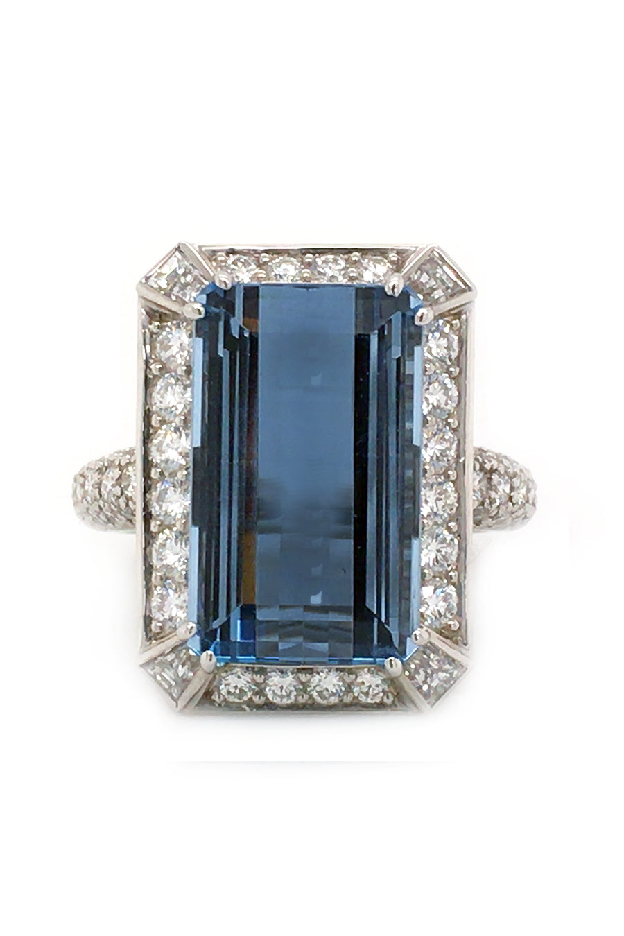 An emerald-cut aquamarine with round diamonds set in a platinum  on a white background