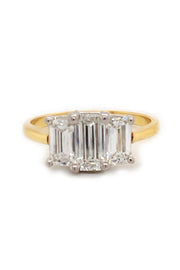 18K yellow gold and platinum ring with three emerald-cut diamonds on a white background