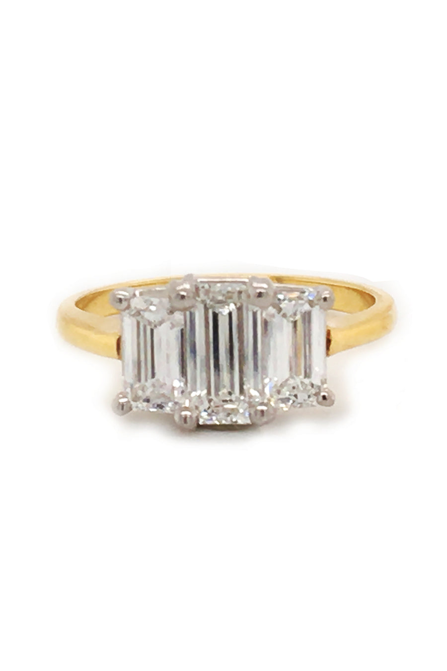 18K yellow gold and platinum ring with three emerald-cut diamonds on a white background