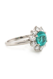 Angle view of platinum ring with paraiba surrounded by diamonds on white background
