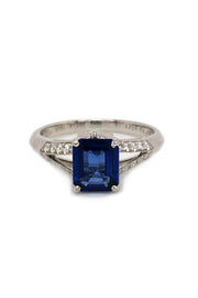 Platinum ring with emerald-cut sapphire and diamonds on white background