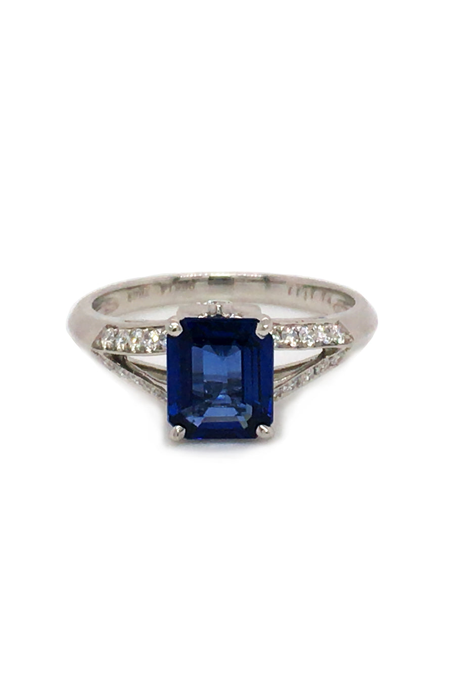 Platinum ring with emerald-cut sapphire and diamonds on white background